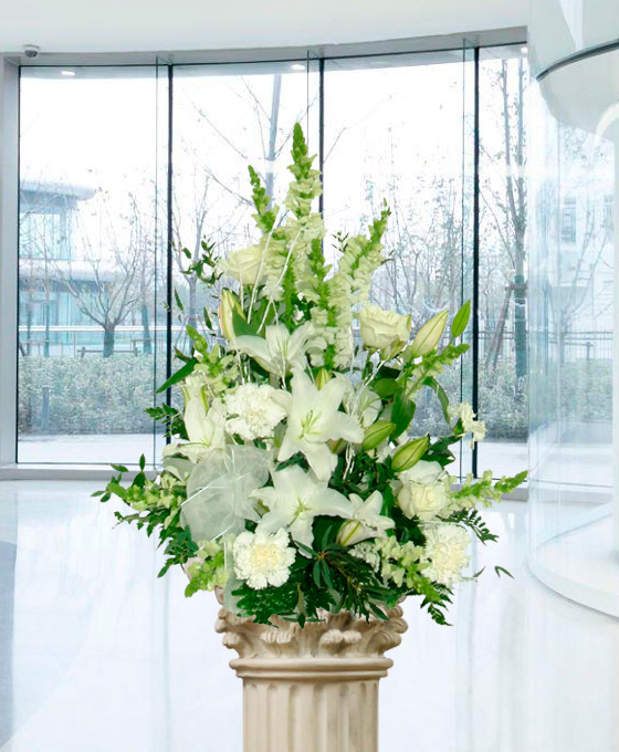 Centro floral de liliums, claveles y rosas blancas con verdes variados