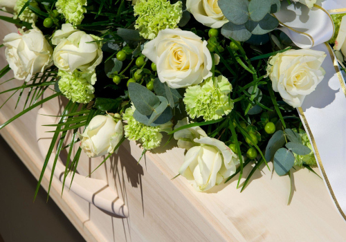 Flores funerarias blancas sobre un ataúd de madera
